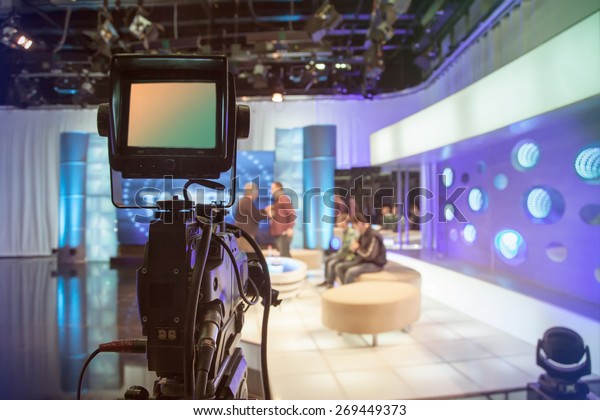 Television studio with camera and\
lights - recording TV show. Shallow depth of field - focus on\
camera