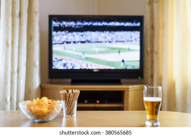 Television, TV Watching (baseball Match) With Snacks And Alcohol Lying On Table - Stock Photo