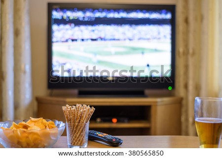 Television, TV watching (baseball match) with snacks and alcohol lying on table - stock photo