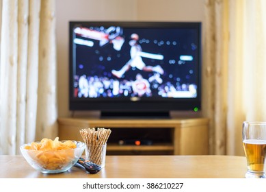 Television, TV Watching (basketball Game) With Snacks And Alcohol Lying On Table - Stock Photo