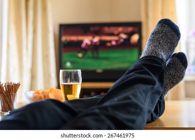 Television, TV watching (football match) with feet on table and huge amounts of snacks - stock photo