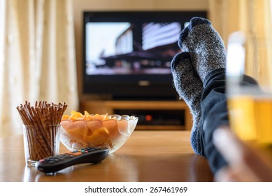 Television, TV Watching (movie) With Feet On Table And Huge Amounts Of Snacks - Stock Photo