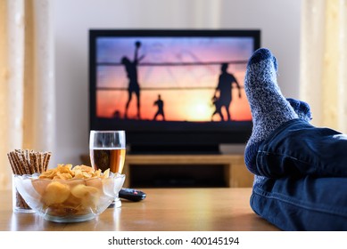 Television, TV Watching (volleyball Match) In Living Room With Feet On Table - Stock Photo