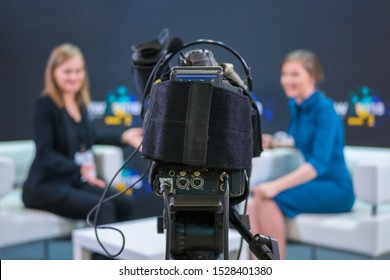 Television Video Camera Recording Interview In Broadcast News Studio. Blurred Background. Media, Production, TV And Broadcast Concept