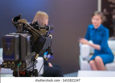 Television Video Camera Recording Interview In Broadcast News Studio. Blurred Background. Media, Production, TV And Broadcast Concept