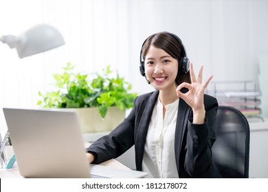 telework concept - asian business woman wears headset smile to you with ok gesture in the office - Powered by Shutterstock