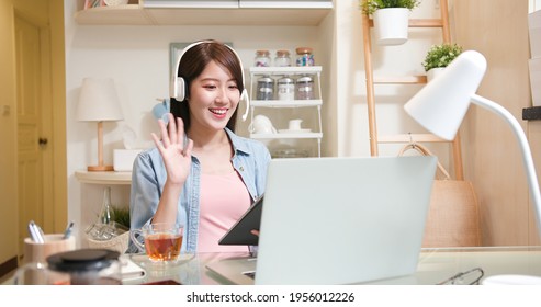 Telework Concept - Asian Business Woman Uses Laptop Computer To Join Video Meeting With Headset And Digital Tablet At Home