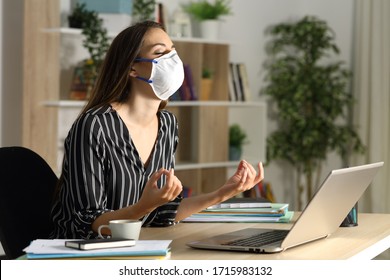 Teleworker With Protective Mask Stress Relieving Due Covid-19 Doing Yoga At Night Sitting On A Desk At Home Office