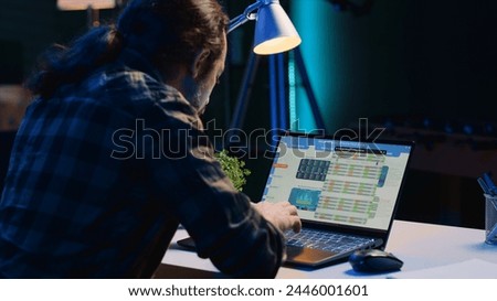 Teleworking financial advisor analyzing statistical charts on laptop screen in living room. Remote worker using notebook to compare business revenue numbers at personal office desk, camera A