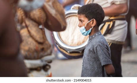 Teluk intan, Perak, Malaysia - April 16 2022 : Young Indian boy stands with in Thaipusam crowd wearing Covid-19 protection mask