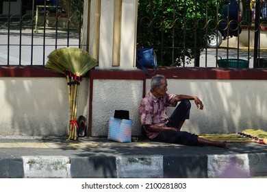 Temanggung - Dec 23, 2021 - Selective focus, an old man wearing batik clothes who sells brooms on the roadside path
