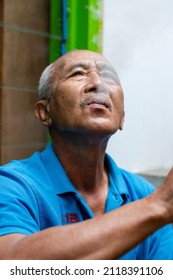 Temanggung, Indonesia - February 5, 2022: An Old Man Blowing Cigarette Smoke