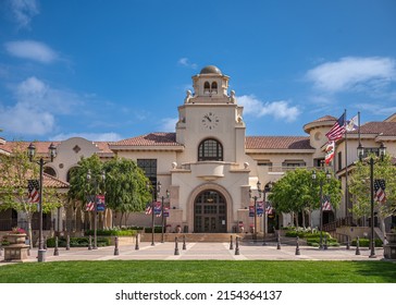 Temecula, CA, USA - April 11, 2022: Old Town neighborhood. Town hall building with clock tower and green lawn up front under blue cloudscape. Line of USA flags to honor fallen heroes.