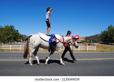 Temecula, California, USA, July 4, 2016, A Young Girl Stands on an Appaloosa Horse wearing an Uncle Sam Hat in a Fourth of July Parade