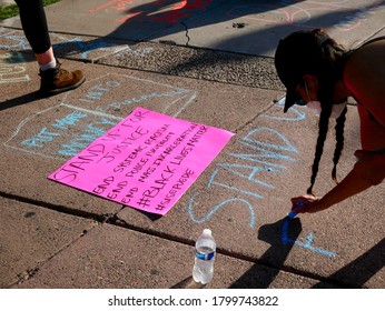 TEMPE, AZ/USA - JULY 2nd, 2020: Young Unidentified Woman With Hat, Sun Glasses, Pony Tails & Face Mask Writes A Message On Concrete Outside Of Tempe City Hall. Chalk Walk In Support Of BLM.