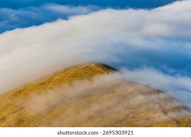 Temperature inversion clouds flowing over a mountain ridge in the Brecon Beacons, Wales
