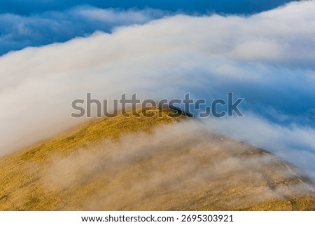 Temperature inversion clouds flowing over a mountain ridge in the Brecon Beacons, Wales
