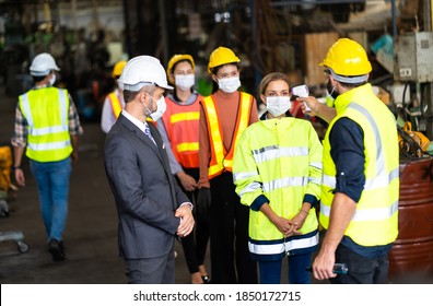 Temperature measurement with employee temperature meter before entering work at factory. Professional engineering team. - Shutterstock ID 1850172715