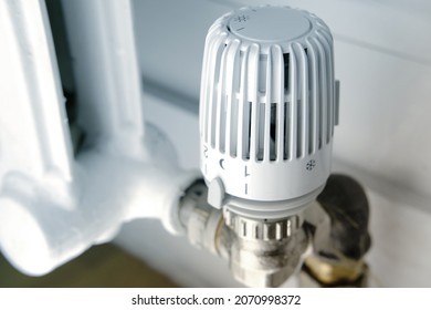 temperature regulation in the house with a thermostat on the white radiator, close-up valve, concept of saving heat, the beginning of the heating season, shallow depth of field focus
