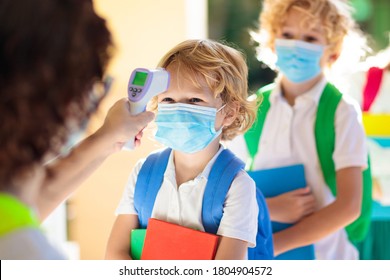 Temperature Screening And Medical Check At School. Child In Face Mask In Class In Covid-19 Outbreak. Teacher With Thermometer At Preschool Entrance. Social Distancing. Coronavirus Prevention.