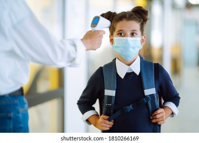 Temperature screening and medical check at school. Schoolgirl in medical mask in class in covid-19 outbreak. Teacher with thermometer at school. - Powered by Shutterstock