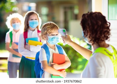 Temperature Screening And Medical Check At School. Child In Face Mask In Class In Covid-19 Outbreak. Teacher With Thermometer At Preschool Entrance. Social Distancing. Coronavirus Prevention.