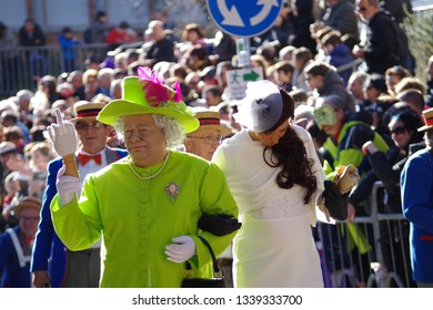 Tempio Pausania, Sardinia / Italy - 03 03 2019 : Man Disguised As Queen Elizabeth In A Lime Yellow Dress Arm In Arm With A Girl Dressed As Kate Middleton In A White Dress At The Carnival Parade