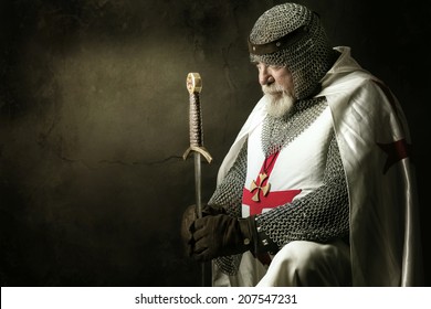 Templar knight praying in a dark background