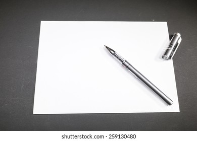 Template blank sheet of paper and a pen on a dark background