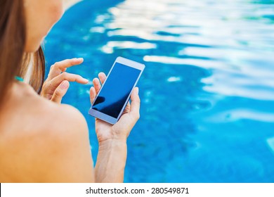 template for a smart phone app: woman using her phone while sitting at poolside - Powered by Shutterstock