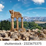 Temple of Dioscuri (Castor and Pollux) with Agrigento town in the Background. Famous ancient ruins in Valley of Temples, Agrigento, Sicily, Italy. UNESCO World Heritage Site.