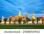 The Temple of the Emerald Buddha at dusk from lawn Sanam Luang in Bangkok, Thailand