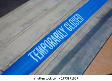 Temporarily closed caution tape. Closed due to Covid-19. Information notice sign about quarantine measures. Close up on a closed caution tape. Blue and White Caution Tape. 