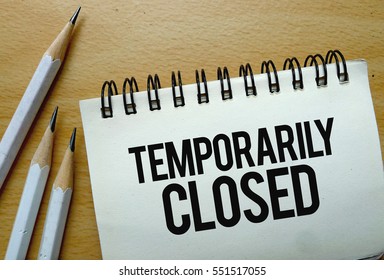 Temporarily Closed text written on a notebook with pencils