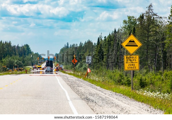 Temporary condition road warning signs on the\
roadside before road work zone, rumble strips on a bilingual yellow\
sign, Canadian rural\
roads