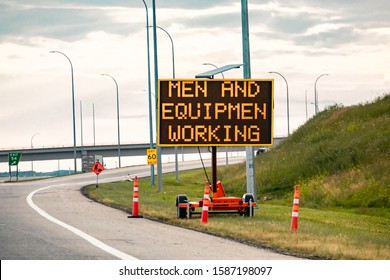 Temporary Condition Variable Message Sign With Orange Barrels On The Right Roadside Men And Equipment Working, Work Zone On The Canadian Highway Roads