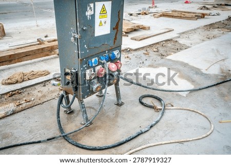 Temporary industrial electrical distribution panel with power sockets and heavy cables at construction site, workplace electricity and safety equipment concept