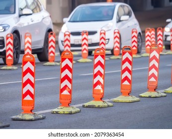 Temporary orange road bollards. Modification of traffic in order to narrow the carriageway. Road works. Cars drive past orange limit posts. Selective focus