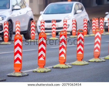 Temporary orange road bollards. Modification of traffic in order to narrow the carriageway. Road works. Cars drive past orange limit posts. Selective focus