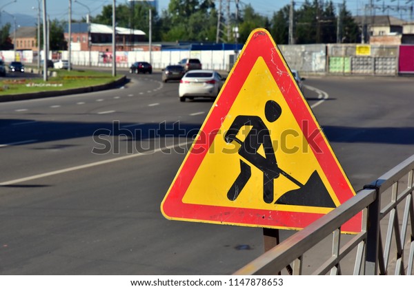 Temporary signal road sign REPAIR WORKS on a city\
street against\
traffic