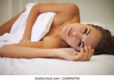 Tempted To Stay In Bed All Day. An Attractive Woman Lying In Bed With Only A Sheet To Cover Her.