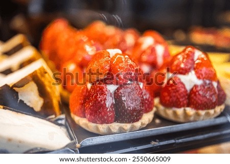 tempting array of freshly baked strawberry tarts fills the display case at local bakery. Each tart has golden crust filled juicy strawberries that sparkle day. Treat yourself to these delicious treats