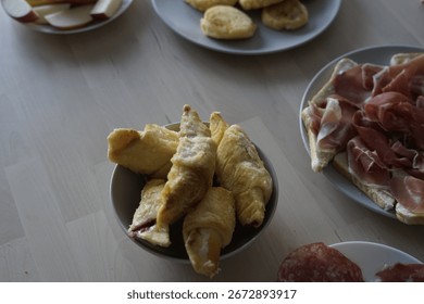 A tempting breakfast spread featuring flaky pastries, assorted meats, and fresh apples, perfect for a delightful morning meal.