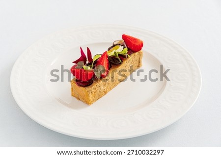 A tempting dessert slice with smooth texture, fresh strawberries, and colorful greens entices all.