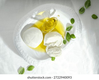 A tempting spread features soft mozzarella, rich burrata, and delicate fior di latte drizzled with golden olive oil, surrounded by fresh basil leaves on a crisp white tablecloth