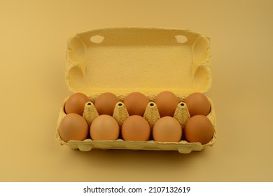 Ten brown eggs in an open cardboard box on a beige background, a place to copy. Chicken eggs in a paper box. Farm chicken eggs. Healthy food, animal protein. Easter eggs, preparation for coloring