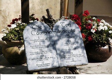 Ten Commandment tablets among pots of flowers.