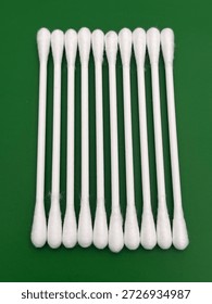 Ten cotton tips on solid green coloured background