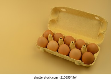 Ten eggs in an open cardboard box on a beige background, a place to copy. Chicken eggs in a paper box. Farm hen eggs. Healthy food, animal protein. Easter eggs brown color