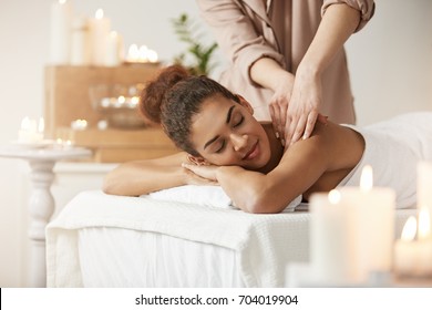 Tender african girl smiling enjoying massage with closed eyes in spa resort.